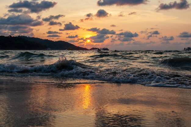 Un paysage incroyablement pittoresque avec une vue sur les vagues de l'océan et le soleil de bronze à l'heure d'or au coucher du soleil en Thaïlande sur l'île de Phuket Patong plage