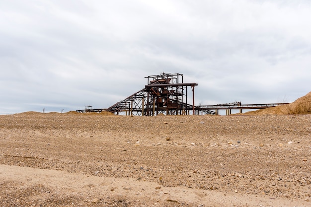 Paysage industriel du désert avec séparateur gravitationnel rouillé stationnaire de sable et de gravier à l'horizon