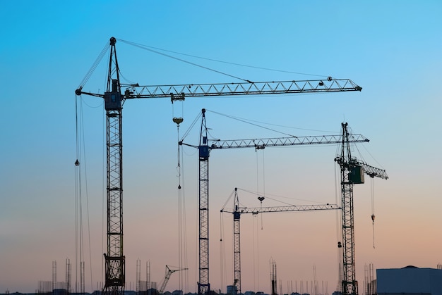 Paysage industriel avec des silhouettes de grues sur le ciel coucher de soleil