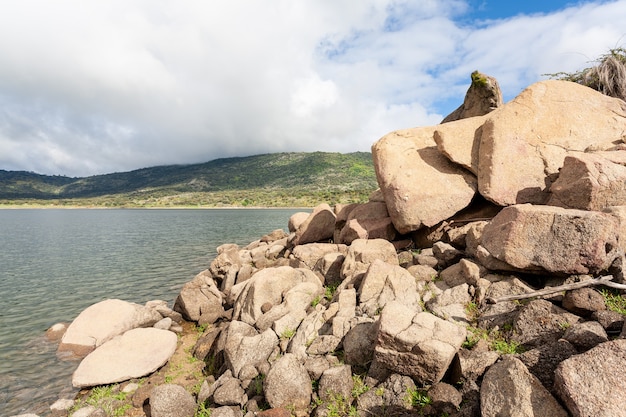 Paysage d'un lac avec un gros plan de rochers de granit entassés sur la rive