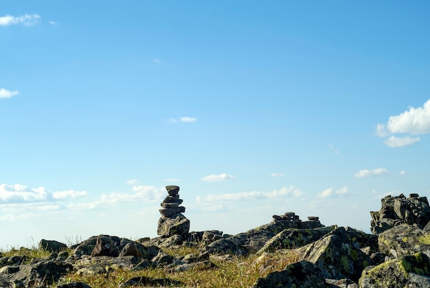 Paysage lumineux d'un plateau de haute altitude avec un cairn de pierres de pyramide plié