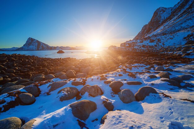 Paysage avec un magnifique coucher de soleil d'hiver et des rochers enneigés sur les îles Lofoten dans le nord de la Norvège.