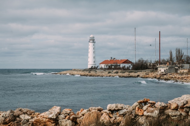 Photo paysage marin coloré avec un phare blanc sur une côte rocheuse au cap chersonese contre un ciel nuageux