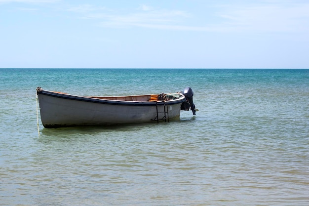 Paysage marin journée ensoleillée plage de sable et ciel nuageux bleu et bateau sur l'eau