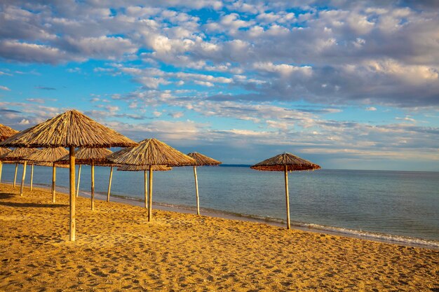 Paysage marin avec des parapluies de paille sur une plage de sable Plage déserte au coucher du soleil