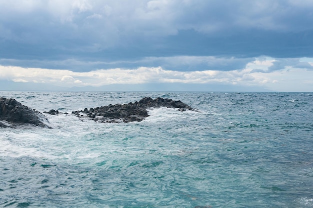 Paysage marin avec des rochers dans les vagues sur un paysage de l'île de Kunashir au premier plan