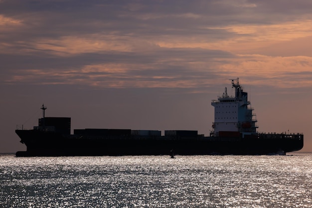 Photo paysage marin et silhouette d'un navire-container flottant en mer