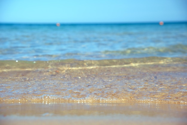 Paysage marin avec une surface d'eau de mer bleue avec de petites vagues d'ondulation se brisant sur une plage de sable jaune. Concept de voyage et de vacances.