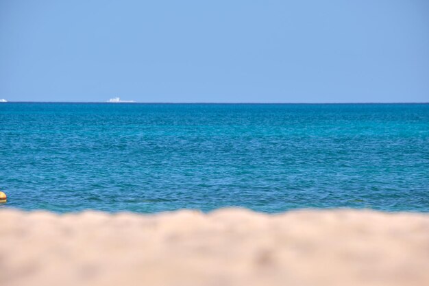 Paysage marin avec surface d'eau de mer bleue avec de petites vagues d'ondulation se brisant sur la plage de sable jaune Concept de voyage et de vacances