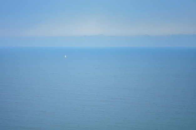 Paysage avec une mer bleue et un voilier est visible au loin