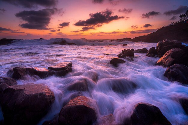 Paysage de la mer avec une longue exposition entouré de rochers lors d'un coucher de soleil à couper le souffle