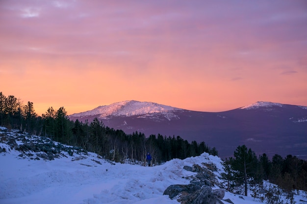 Paysage de montagne d'aube d'hiver avec une fille de randonneur marchant le long de la route