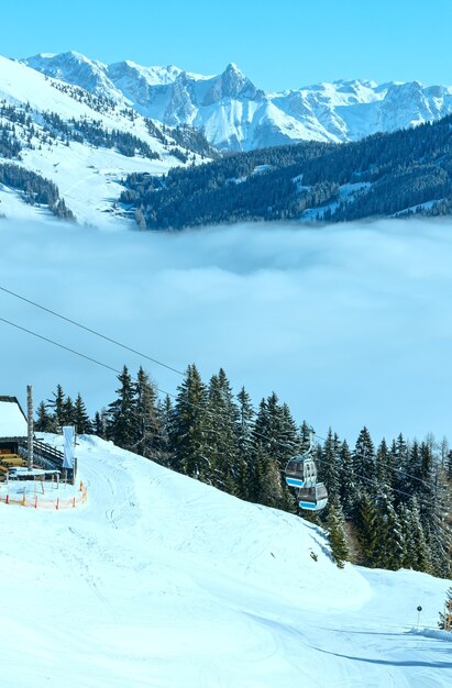 Paysage de montagne ensoleillé d'hiver et remontées mécaniques sur la colline (Autriche)