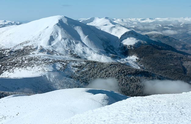 Paysage de montagne d'hiver ensoleillé du matin avec des nuages bas sur la crête (Carpates, Ukraine).