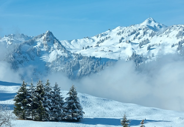 Paysage de montagne d'hiver avec des nuages bas sur la pente (Autriche, Bavière).