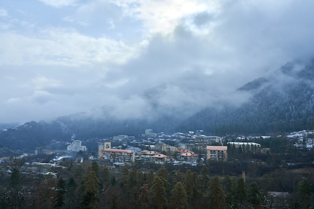 Paysage de montagne d'hiver. Petite ville entre les montagnes. Un nuage plane sur la ville.