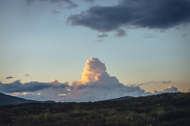 Paysage de montagne impressionnant avec gros nuage orange en forme d'explosion au coucher du soleil. Paysage de lever de soleil avec un beau nuage énorme de couleur éclairante. Vue panoramique sur le nuage géant jaune dans le ciel de l'aube.