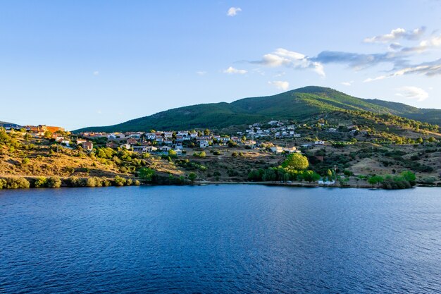 Paysage de montagne avec un lac turquoise et un village.