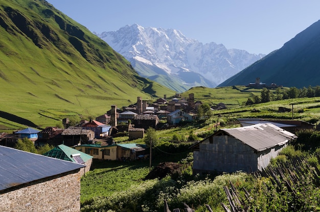 Paysage de montagne avec un pic enneigé. L'ancien village alpin. Journée d'été ensoleillée avec un ciel clair. Le village d'Ushguli et le mont Shkhara. Crête principale du Caucase, Zemo Svaneti, Géorgie