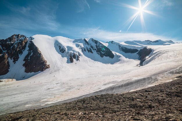 Paysage de montagne pittoresque avec grand glacier au soleil Paysage impressionnant avec langue glaciaire sous le soleil dans le ciel bleu Belle vue alpine sur les sommets des montagnes enneigées à très haute altitude par temps ensoleillé