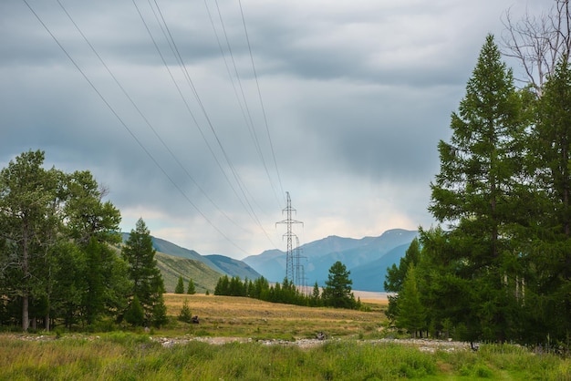 Paysage de montagne spectaculaire avec une grande tour de lignes électriques sous un ciel nuageux Paysage alpin atmosphérique avec une tour électrique avec des fils contre de hautes montagnes dans un ciel couvert Électricité dans les montagnes