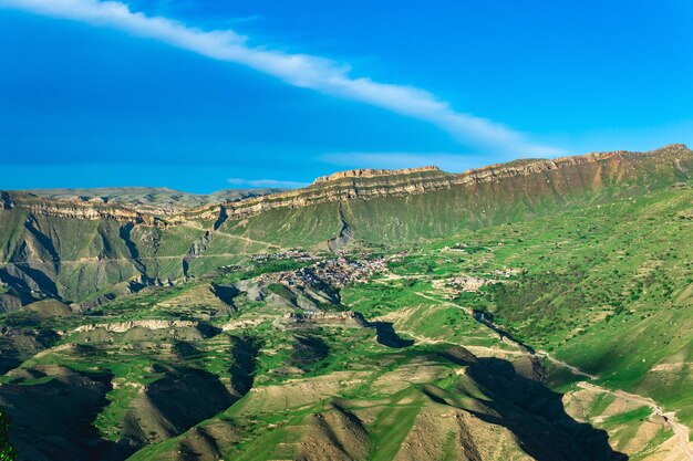 Paysage de montagne avec un village sur une pente sous une énorme crête rocheuse Chokh au Daghestan