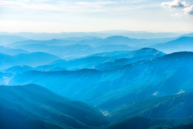 Paysage avec des montagnes bleues, des forêts et des nuages blancs sur le ciel