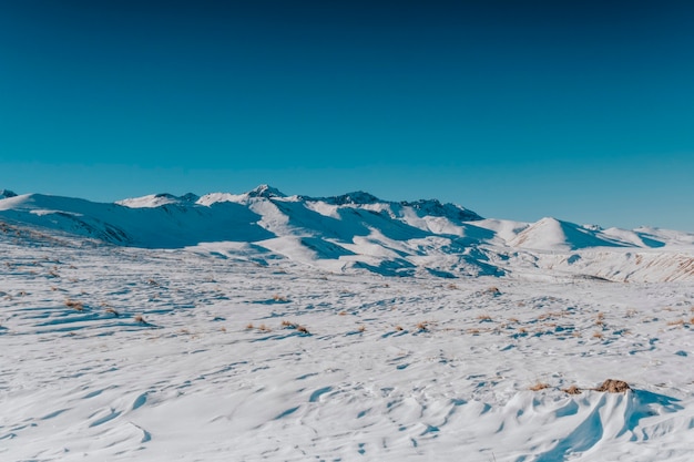 Paysage de montagnes et de collines enneigées d'hiver et de ciel bleu.