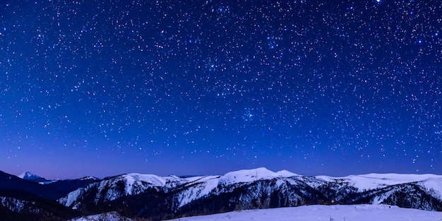 Le paysage montagneux hivernal la nuit est une toile à couper le souffle ornée d'innombrables étoiles