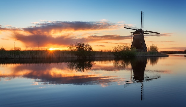 Paysage avec des moulins à vent hollandais traditionnels au lever du soleil coloré, beau ciel