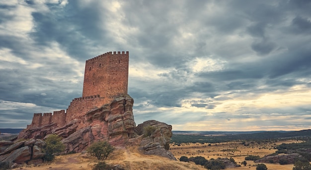 Paysage naturel avec un château médiéval au sommet d'une colline et les rayons du soleil à travers les nuages