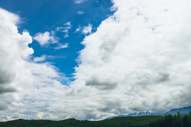 Paysage naturel pittoresque avec de beaux nuages dans le ciel bleu. Cloudscape coloré avec des nuages au-dessus des montagnes enneigées et de la forêt. Fond de nature du ciel avec des nuages blancs. Toile de fond de ciel nuageux naturel.