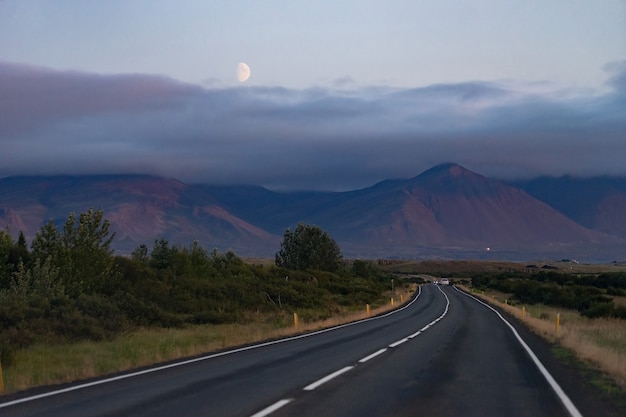 Paysage de nuit pittoresque avec belle route, lune et montagnes de l'Islande Westfjord.