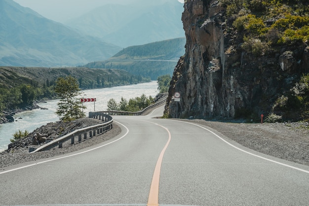 Paysage pittoresque avec panneau de signalisation de limitation de vitesse sur la route de montagne. Belle vue à tracter dans les hauts plateaux. Paysage avec route goudronnée avec marquage routier. Autoroute avec ligne continue et rivière de montagne.