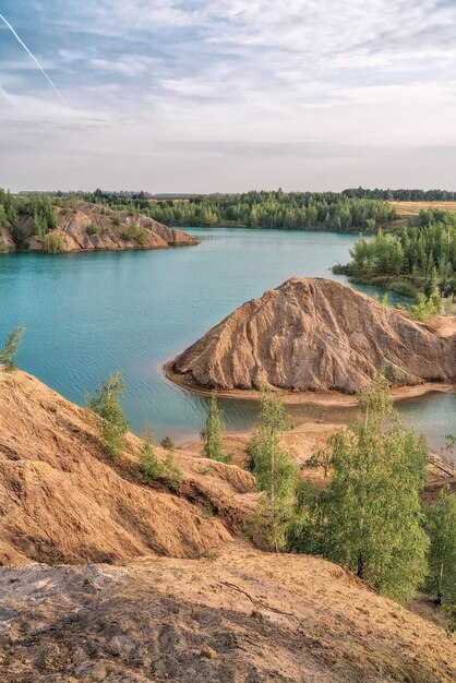 Paysage pittoresque de rochers sablonneux et lac aux eaux claires bleues ou turquoises. Forêt de pins verts sur fond. Carrière de Konduki en Russie. Ciel nuageux. Concept de voyage. photo verticale.