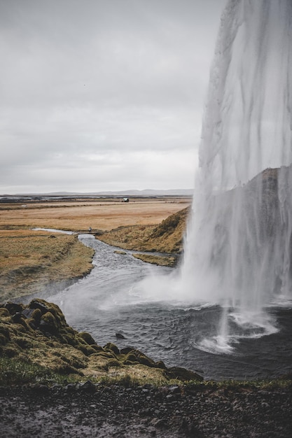 Paysage de route de cascade en Islande avec le fond sauvage de montagnes et de prés