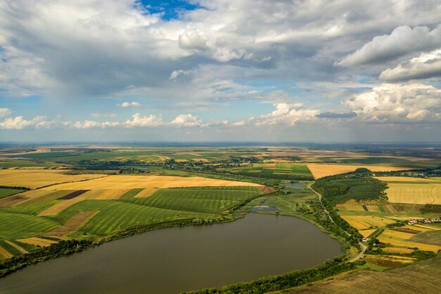 Paysage rural aérien avec des champs d'agriculture rapiécés jaunes et un ciel bleu avec des nuages blancs.