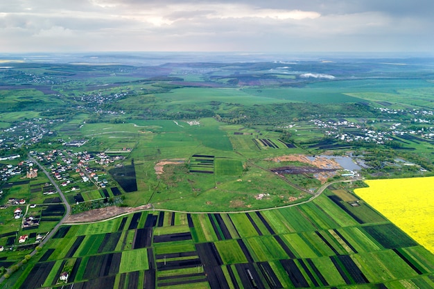 Paysage rural au printemps ou en été. Vue aérienne de champs verts, labourés et fleuris, toits de maisons à l'aube ensoleillée. Photographie de drone.