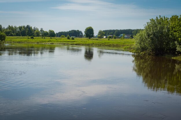 Paysage rural d'été avec rivière et ciel bleu.