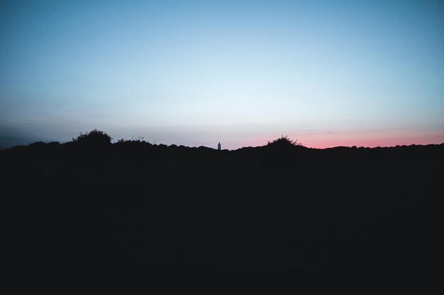 Un paysage en silhouette sur un ciel clair au coucher du soleil