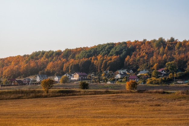 Paysage de soirée ensoleillé avec des terres agricoles prêtes à être plantées, avec un village sur une colline