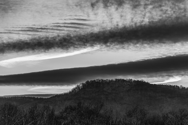 Paysage de soirée d'hiver avec collines et ciel nuageux, photo en noir et blanc