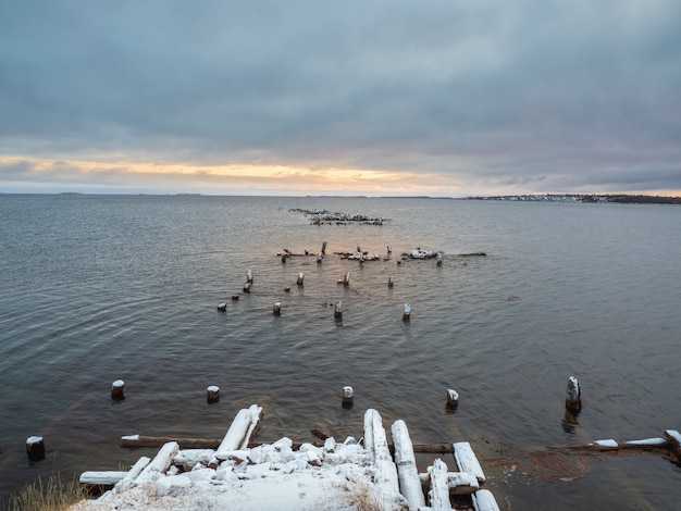 Paysage de soirée d'hiver minimaliste avec une vieille jetée en ruine dans la mer Blanche.