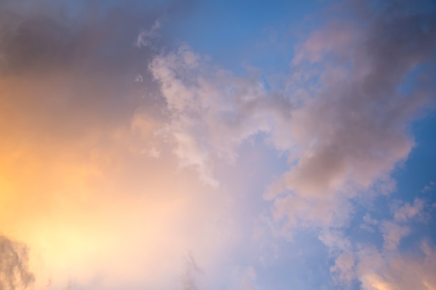 Paysage spectaculaire au coucher du soleil avec des nuages gonflés éclairés par un soleil couchant orange et un ciel bleu.