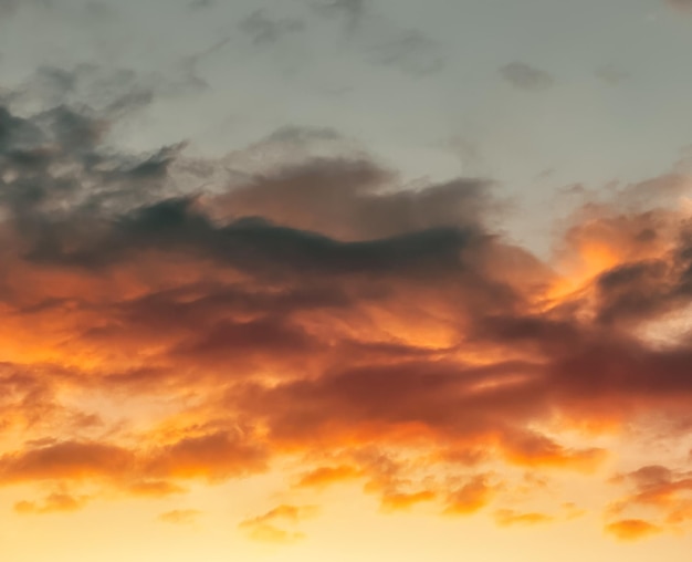 Paysage spectaculaire au coucher du soleil avec des nuages gonflés éclairés par un soleil couchant orange et un ciel bleu