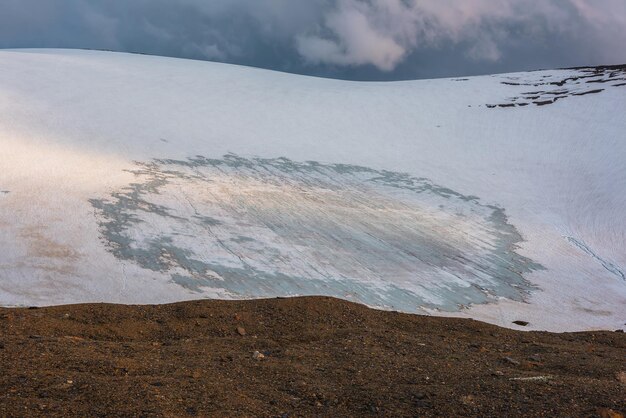 Paysage spectaculaire avec glacier sur une haute montagne enneigée ensoleillée sous un ciel nuageux au coucher du soleil Magnifique paysage alpin avec une grande montagne enneigée au soleil sous les nuages du soir par temps variable