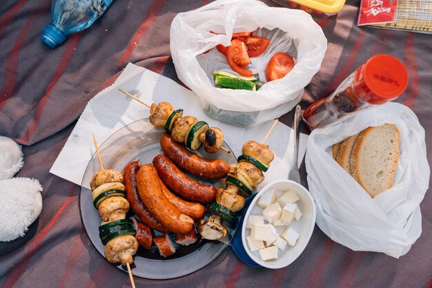 Un paysage de table de table de pique-nique d'été avec des saucisses grillées, des champignons et des courgettes