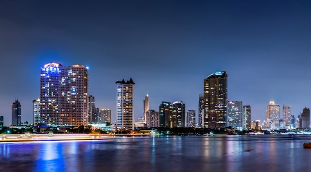 Paysage urbain d'un bâtiment moderne près de la rivière dans la nuit. Immeuble de bureaux d'architecture moderne. Gratte-ciel avec ciel du soir.