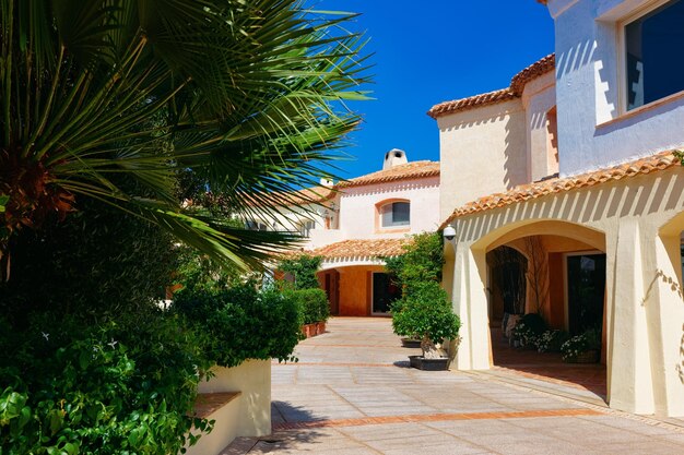 Photo paysage urbain avec palmier et complexe résidentiel. immeuble d'appartements. architecture de maison côtière à porto cervo sur l'île de sardaigne en italie en été. vue sur la ville sarde en sardaigne.