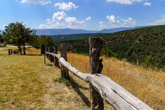 Paysage verdoyant avec clôture en bois, prairies herbeuses et forêts d'arbres, ciel bleu avec des nuages. Espagne.